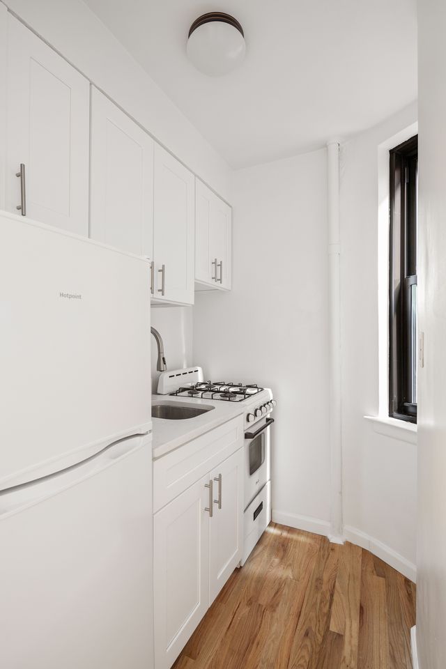 431 West 54th Street, Unit 3C Manhattan, NY 10019 - Photo 3 of 5 a kitchen with granite countertop a stove a sink and a refrigerator