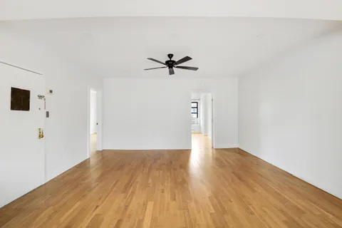 a view of a big room with wooden floor and a ceiling fan
