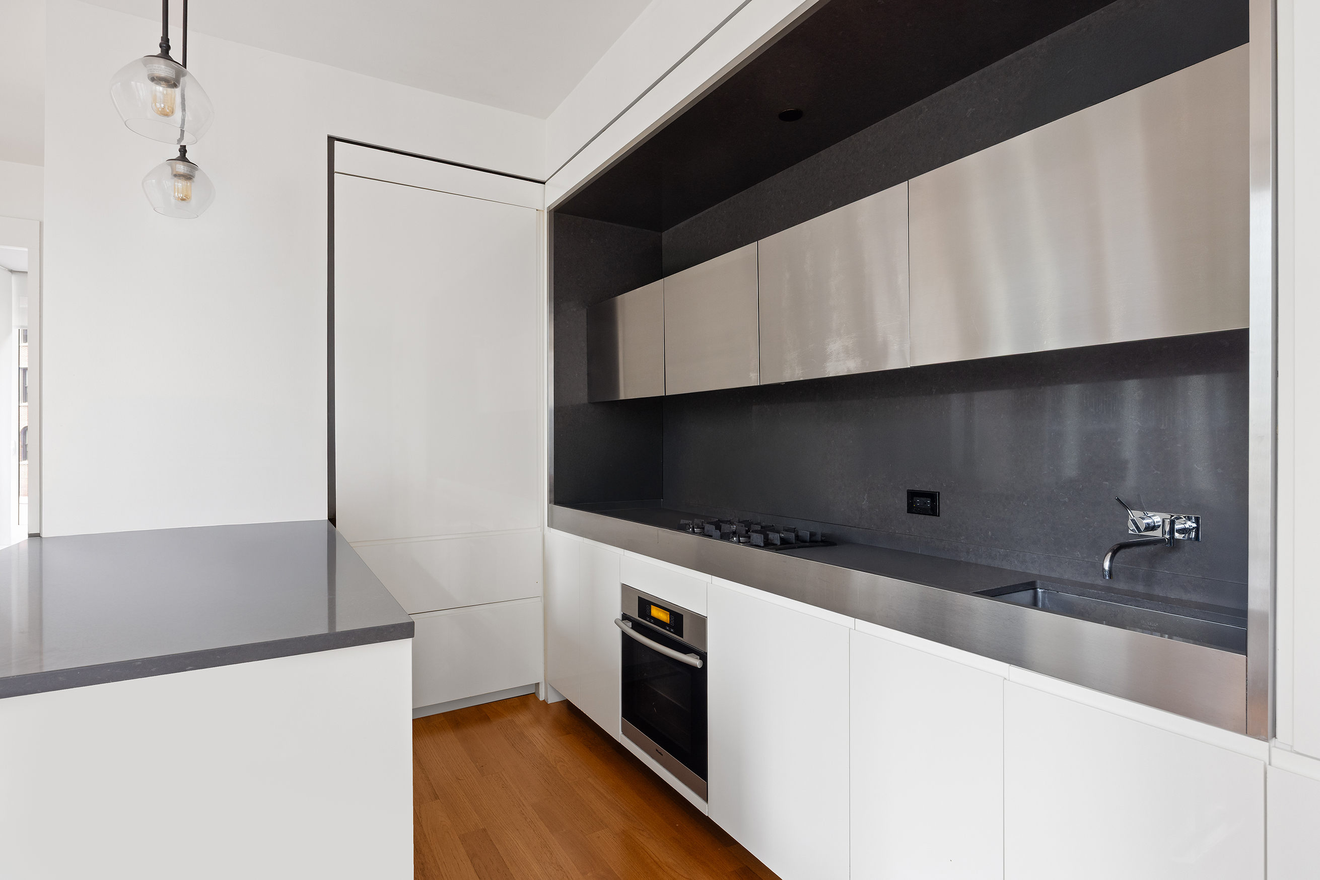 15 William Street, Unit 21A Manhattan, NY 10005 - Photo 4 of 19 a kitchen with stainless steel appliances a refrigerator a stove and a microwave