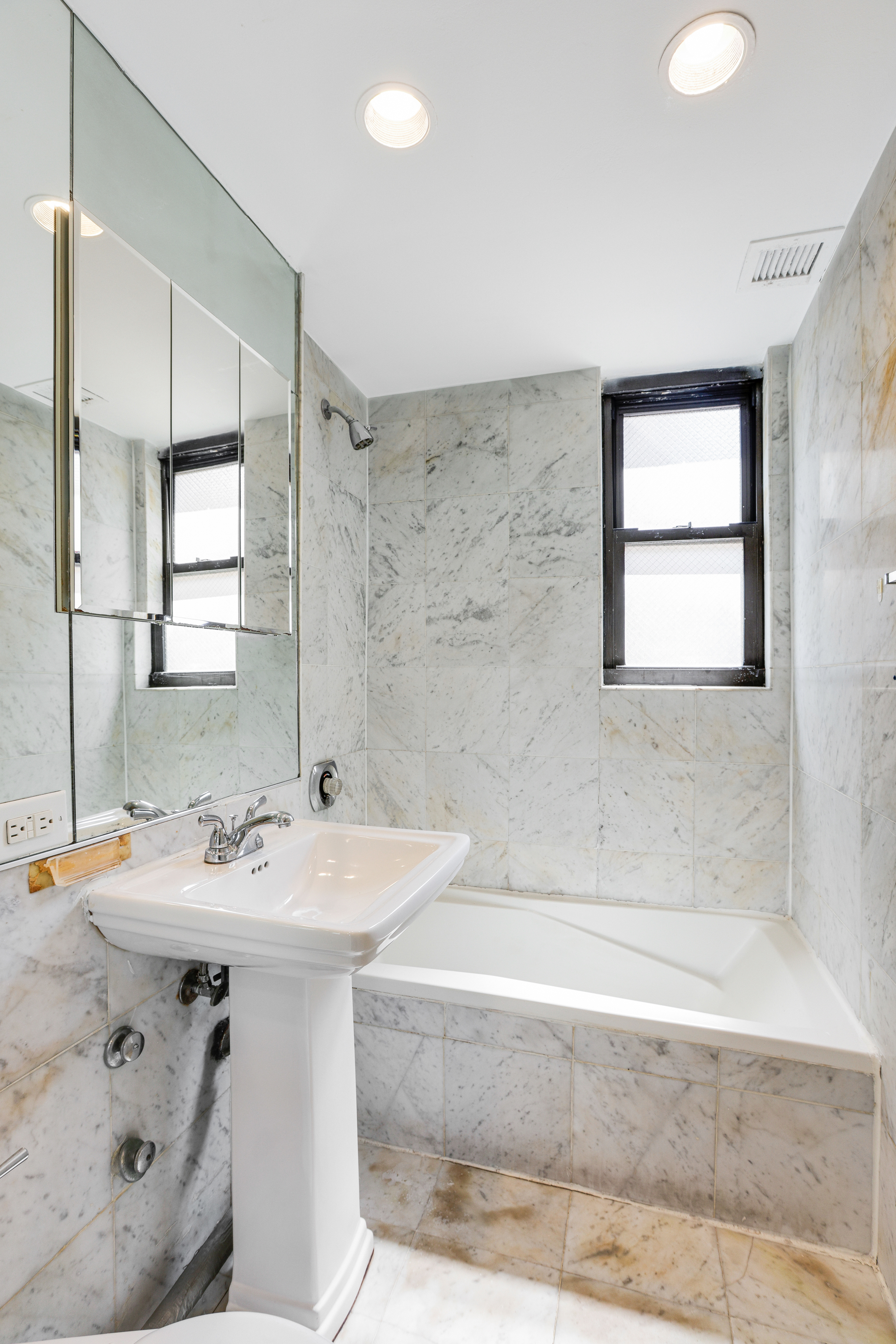 210 East 47th Street, Unit 7J Manhattan, NY 10017 - Photo 10 of 12 a bathroom with a sink mirror and a bathtub
