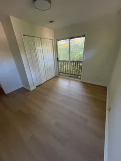 a view of an empty room with wooden floor and windows