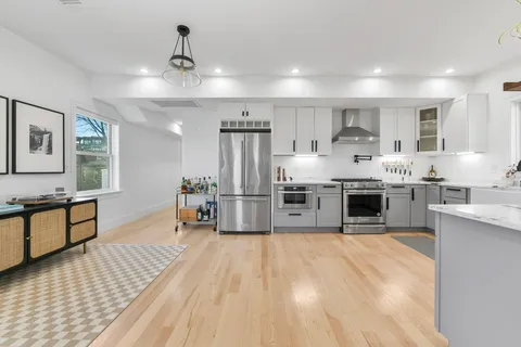 a large kitchen with stainless steel appliances kitchen island a large counter top and a view of living room