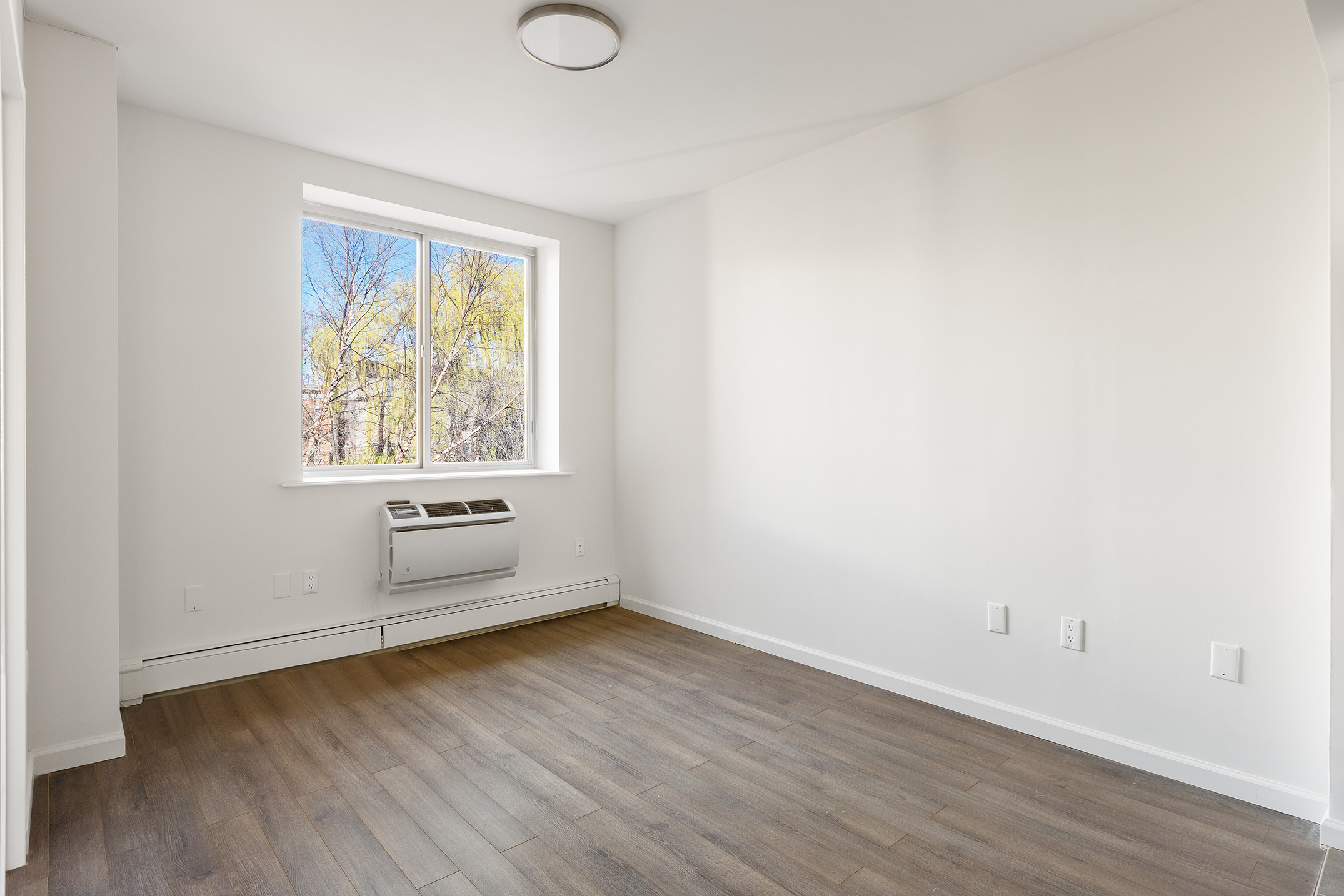 194 East 2nd Street, Unit 3A Manhattan, NY 10009 - Photo 3 of 12 an empty room with wooden floor and windows