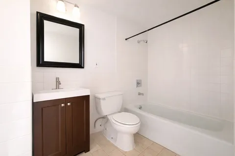 a bathroom with a toilet sink vanity tub and mirror