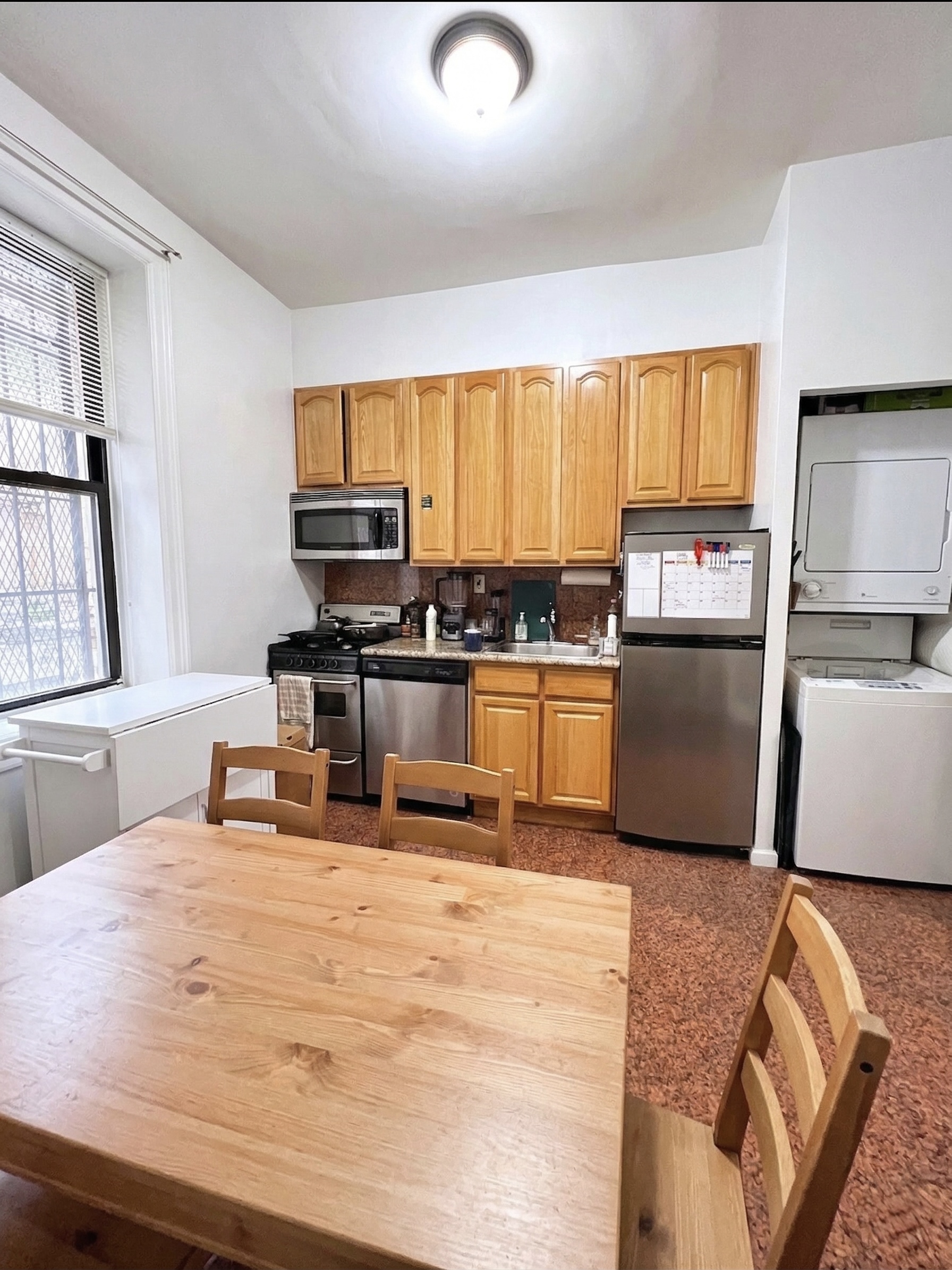 90 Thompson Street, Unit A2 Manhattan, NY 10012 - Photo 2 of 6 a kitchen with stainless steel appliances granite countertop a stove top oven a sink a dining table and chairs with wooden floor