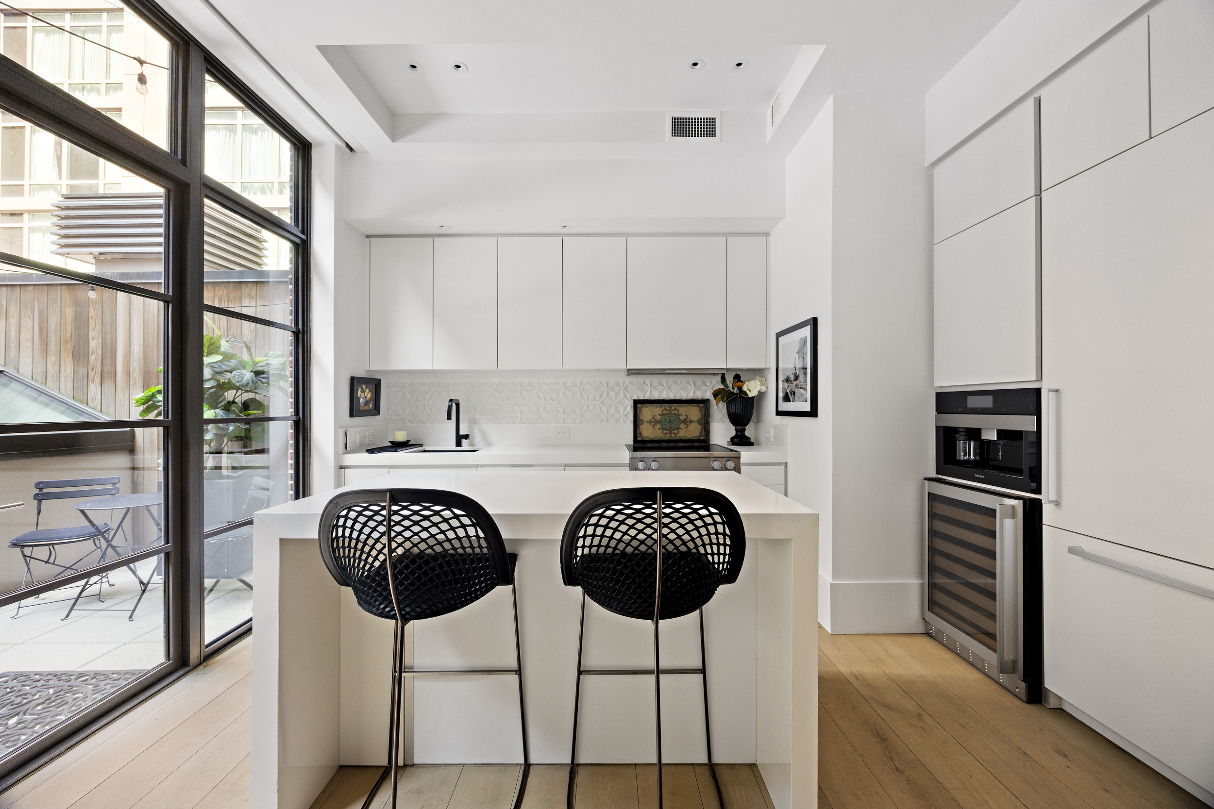 404 Park Avenue South, Unit 3E Manhattan, NY 10016 - Photo 9 of 21 a kitchen with stainless steel appliances a dining table chairs refrigerator and sink