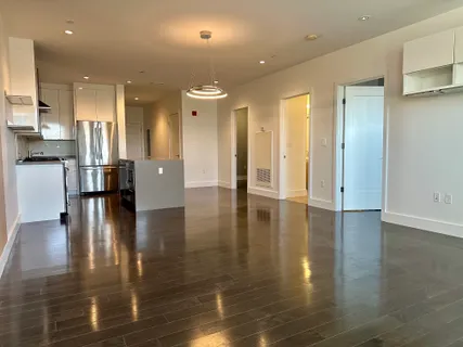 a view of empty room with wooden floor and seating space