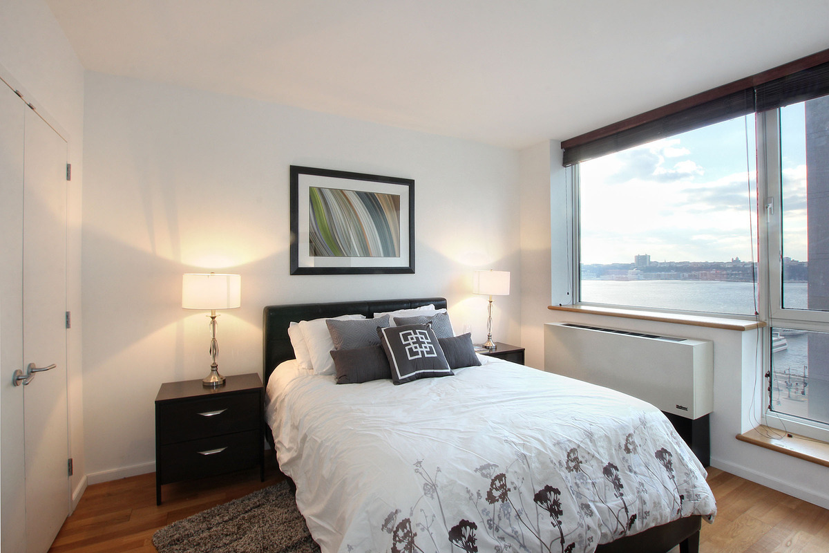 635 West 42nd Street, Unit 10A Manhattan, NY 10036 - Photo 3 of 7 a bedroom with a large bed and wooden floor