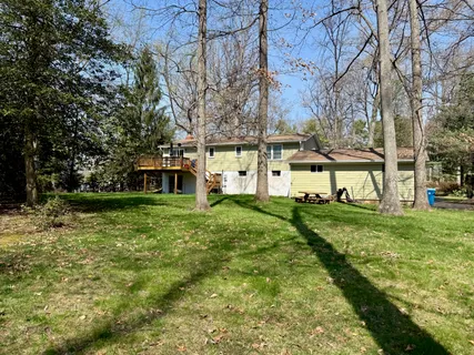 a view of a house with a big yard plants and large trees