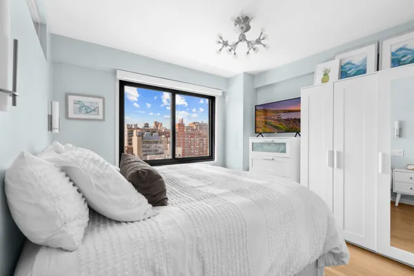 a bedroom with a bed cabinets and a window