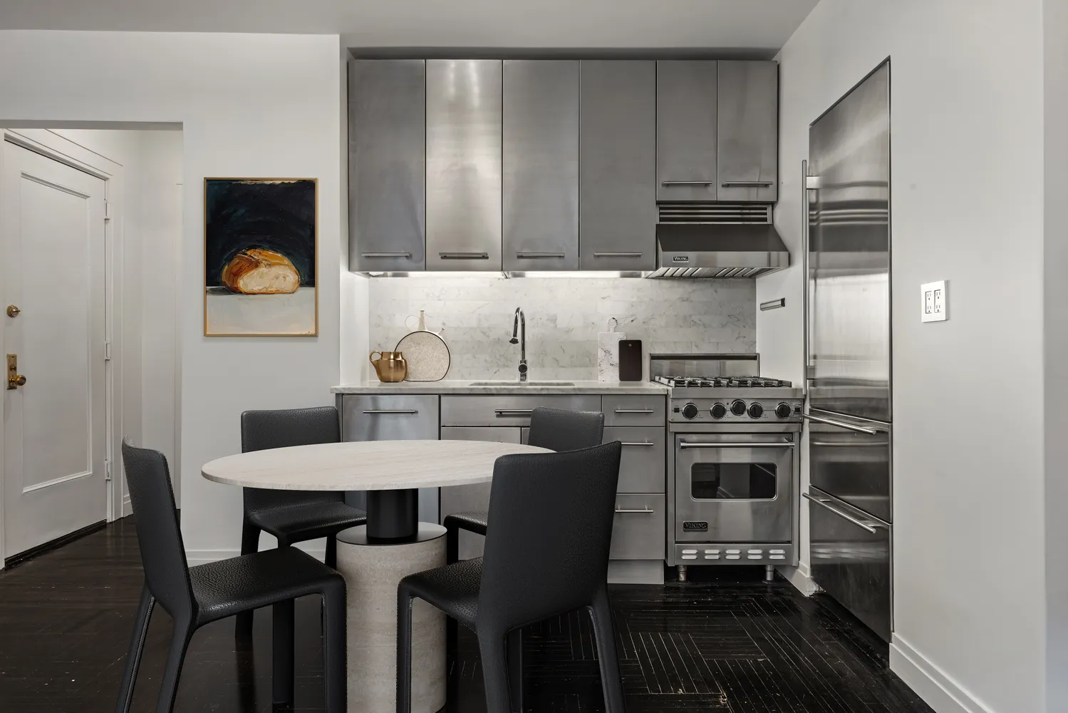 a kitchen with granite countertop a dining table chairs and a refrigerator