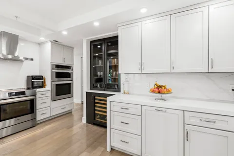 a kitchen with stainless steel appliances white cabinets and wooden floors