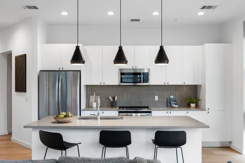 a kitchen with stainless steel appliances granite countertop a sink a stove and chairs