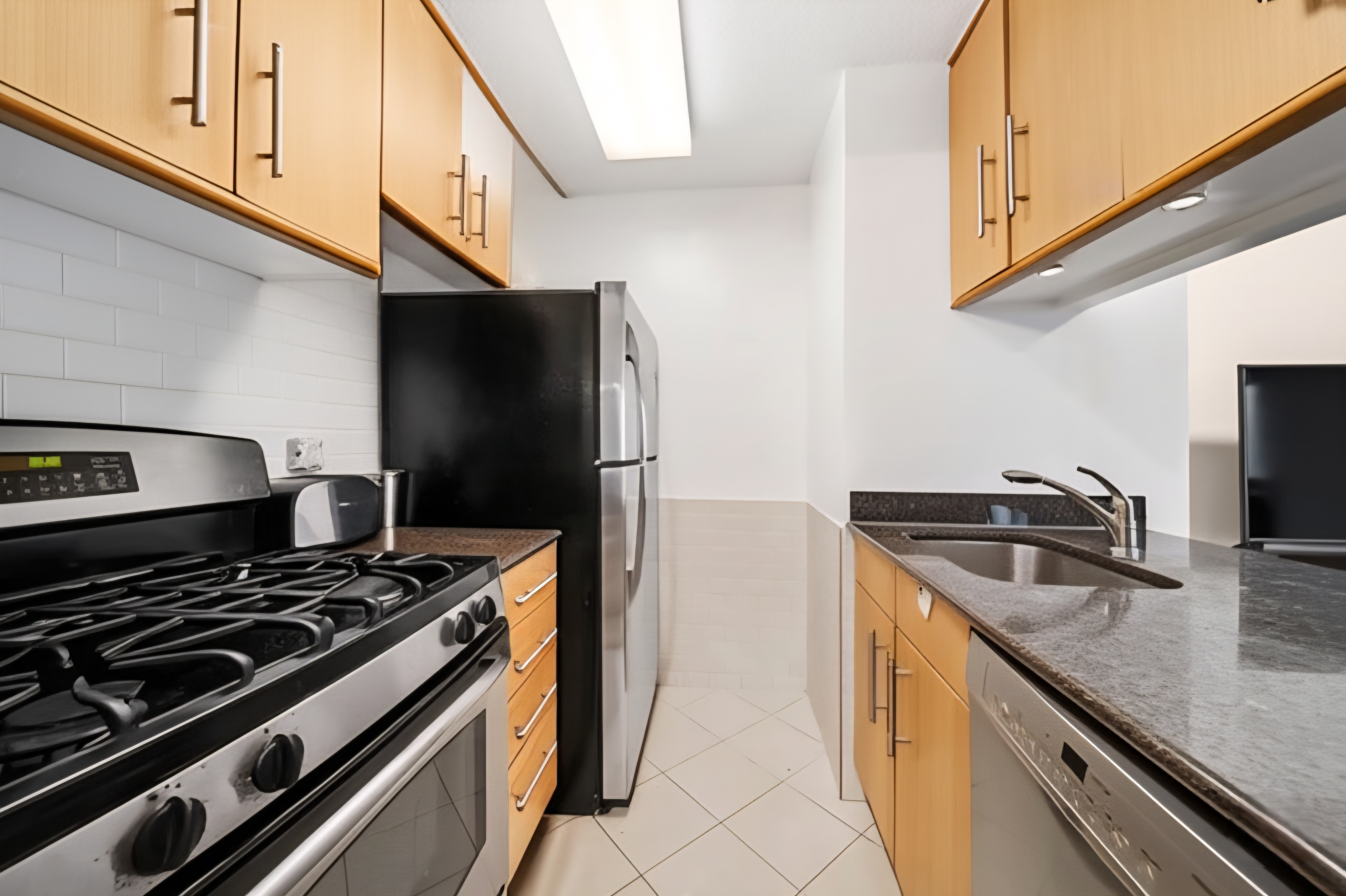200 Rector Place, Unit 6P Manhattan, NY 10280 - Photo 4 of 10 a kitchen with granite countertop a sink stove and refrigerator
