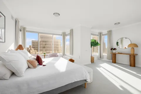 a bedroom with bed and large windows