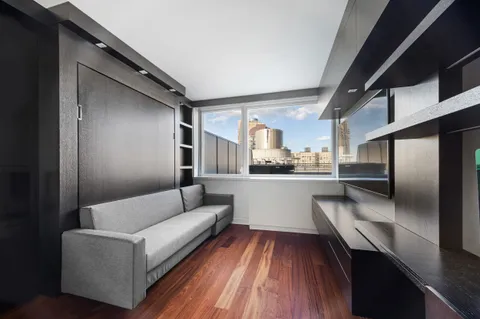 a living room with stainless steel appliances kitchen island granite countertop furniture and a wooden floor