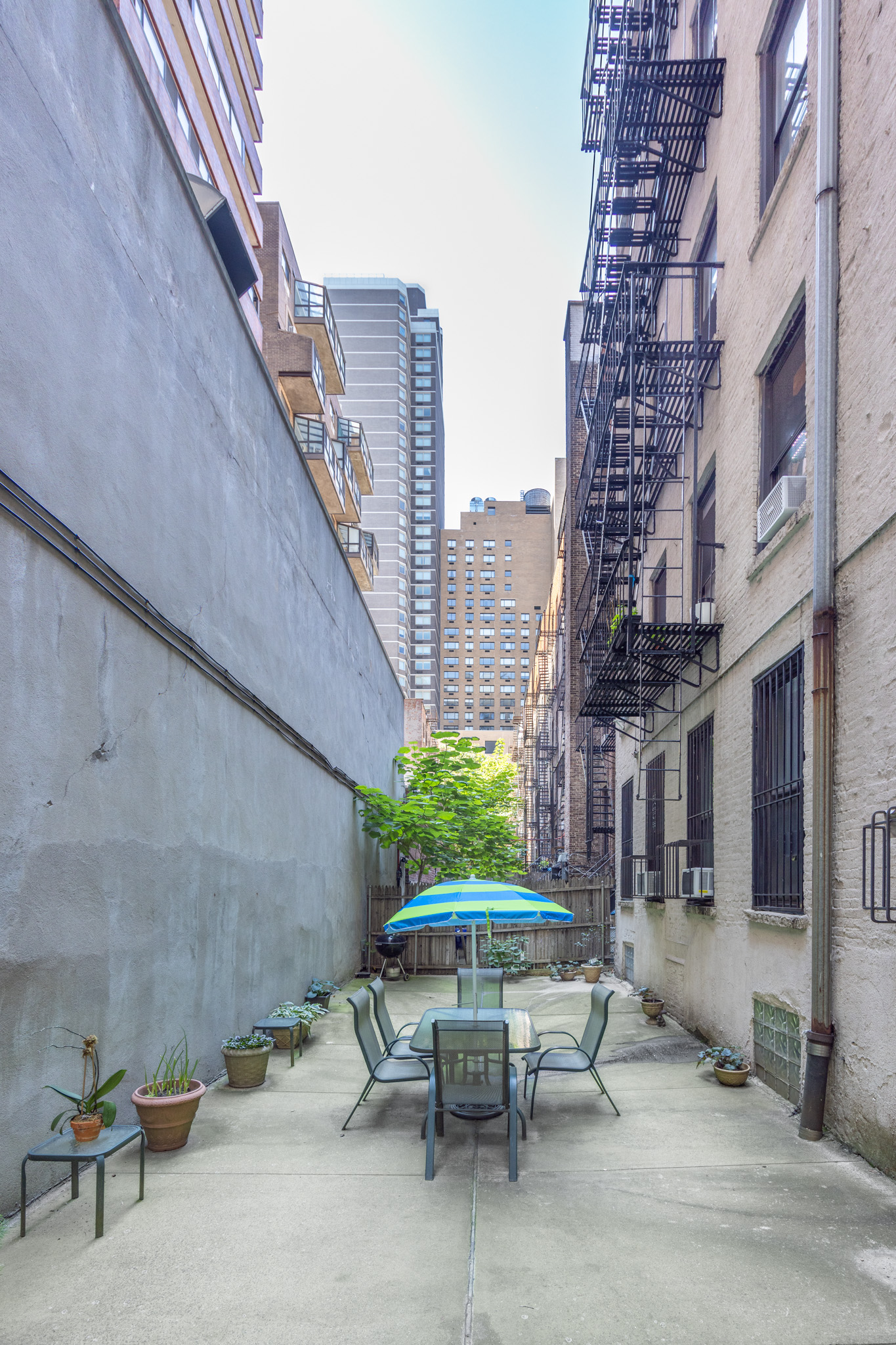 242 East 87th Street, Unit 2B Manhattan, NY 10128 - Photo 8 of 10 a view of a patio with a table and chairs and potted plants