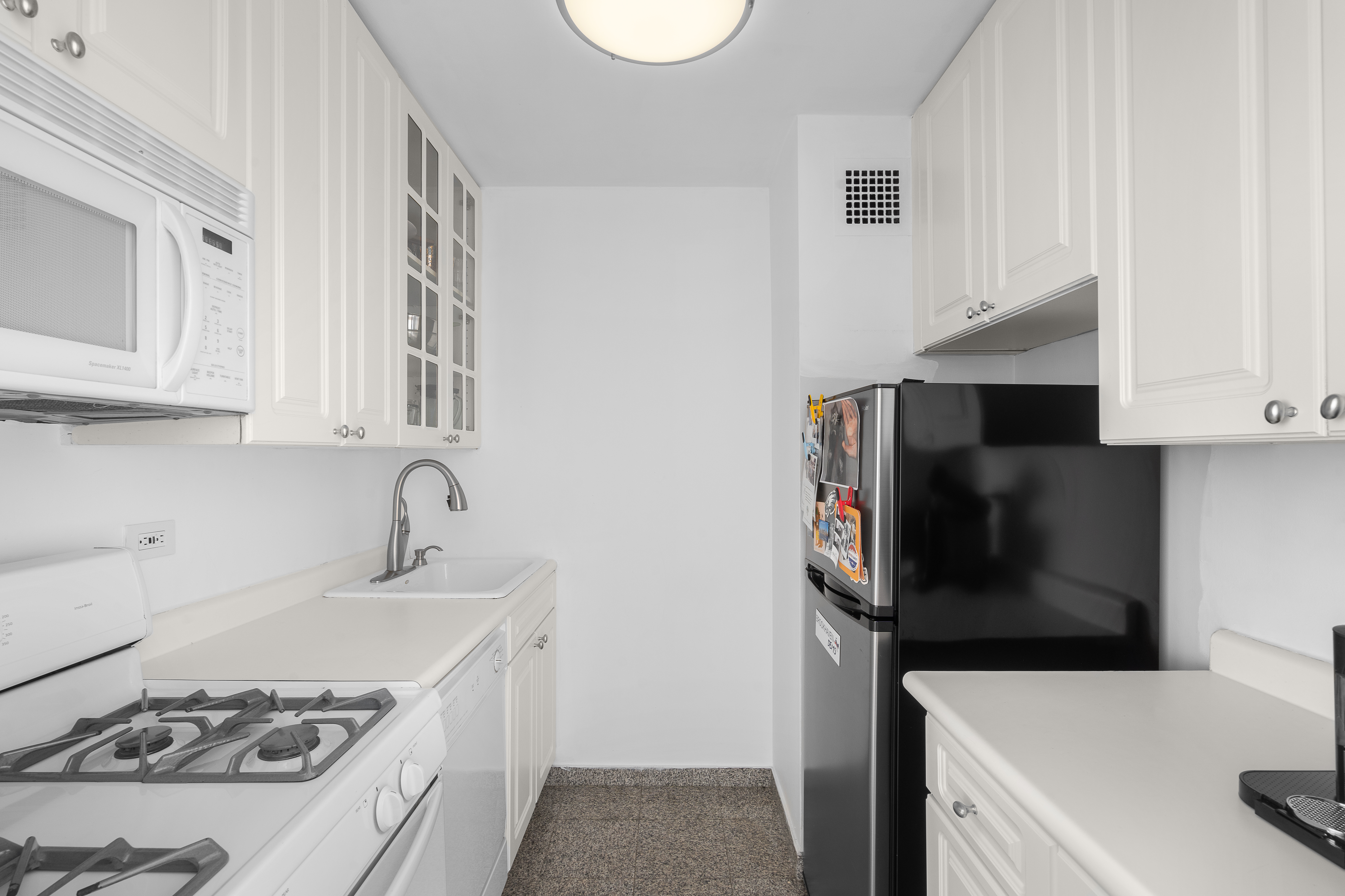 301 East 79th Street, Unit 18C Manhattan, NY 10075 - Photo 6 of 13 a kitchen with stainless steel appliances a white stove top oven a sink and dishwasher