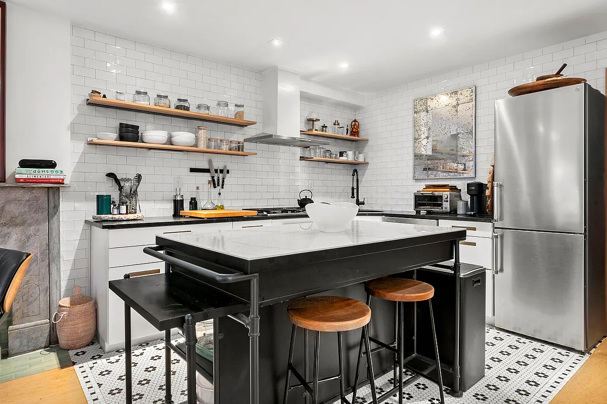 87 Monroe Street, Unit 1 Brooklyn, NY 11216 - Photo 4 of 11 a kitchen with stainless steel appliances a table chairs and a refrigerator