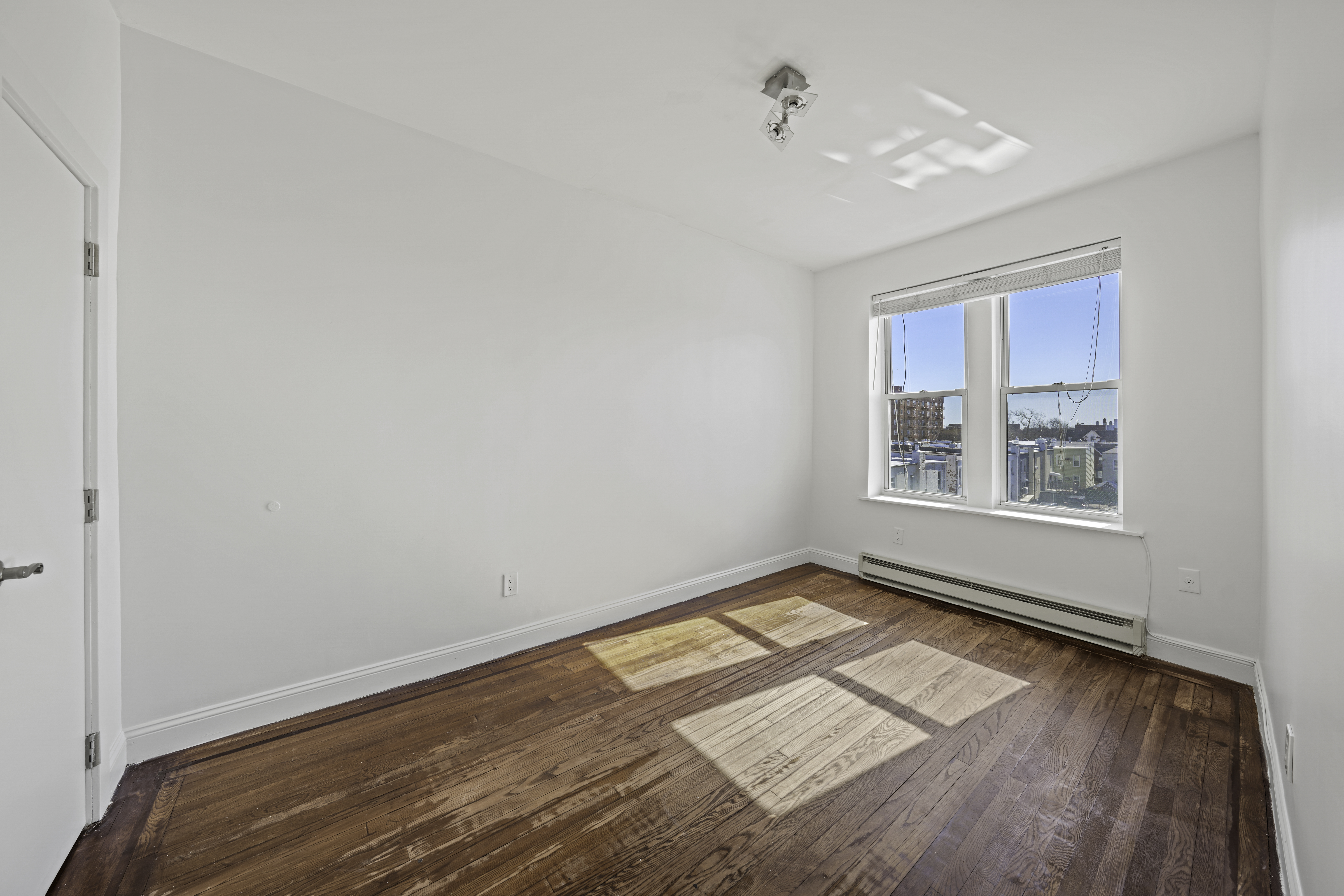 514 86th Street, Unit 4 Brooklyn, NY 11209 - Photo 14 of 19 an empty room with wooden floor and windows