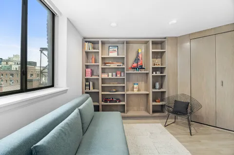a living room with a couch and a bookshelf with wooden floor
