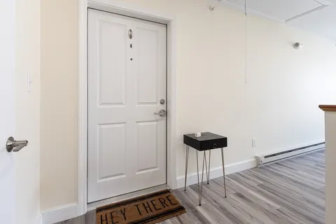 a view of a hallway with wooden floor and a bathroom