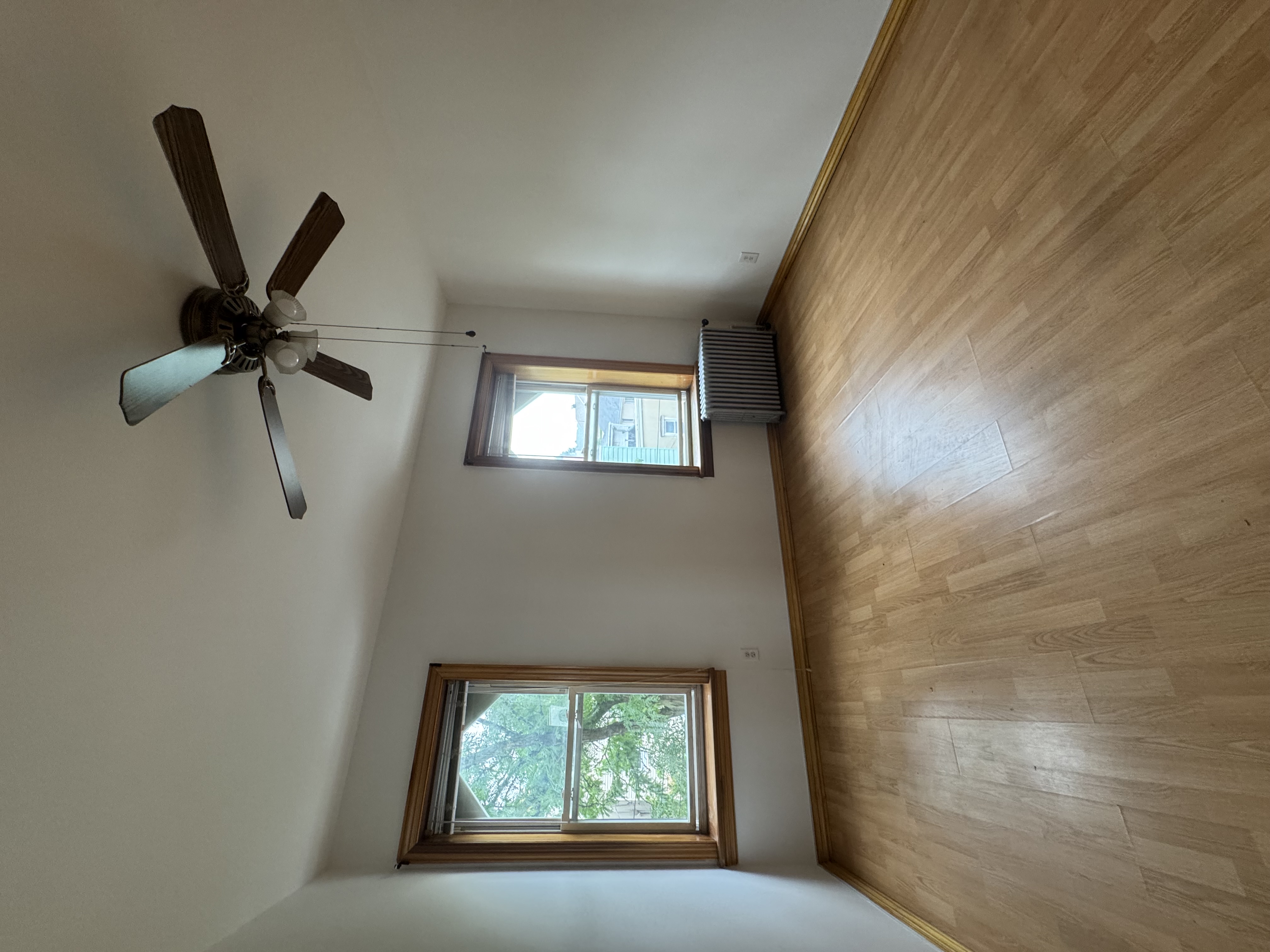 60-27 56th Road, Unit 3 Queens, NY 11378 - Photo 5 of 9 an empty room with wooden floor fan and windows