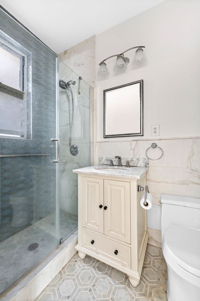 320 East 83rd Street, Unit 4DE Manhattan, NY 10028 - Photo 8 of 12 a bathroom with a granite countertop sink mirror and shower