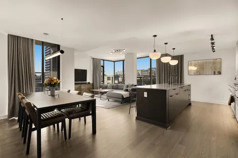 a living room with couches and kitchen view with wooden floor