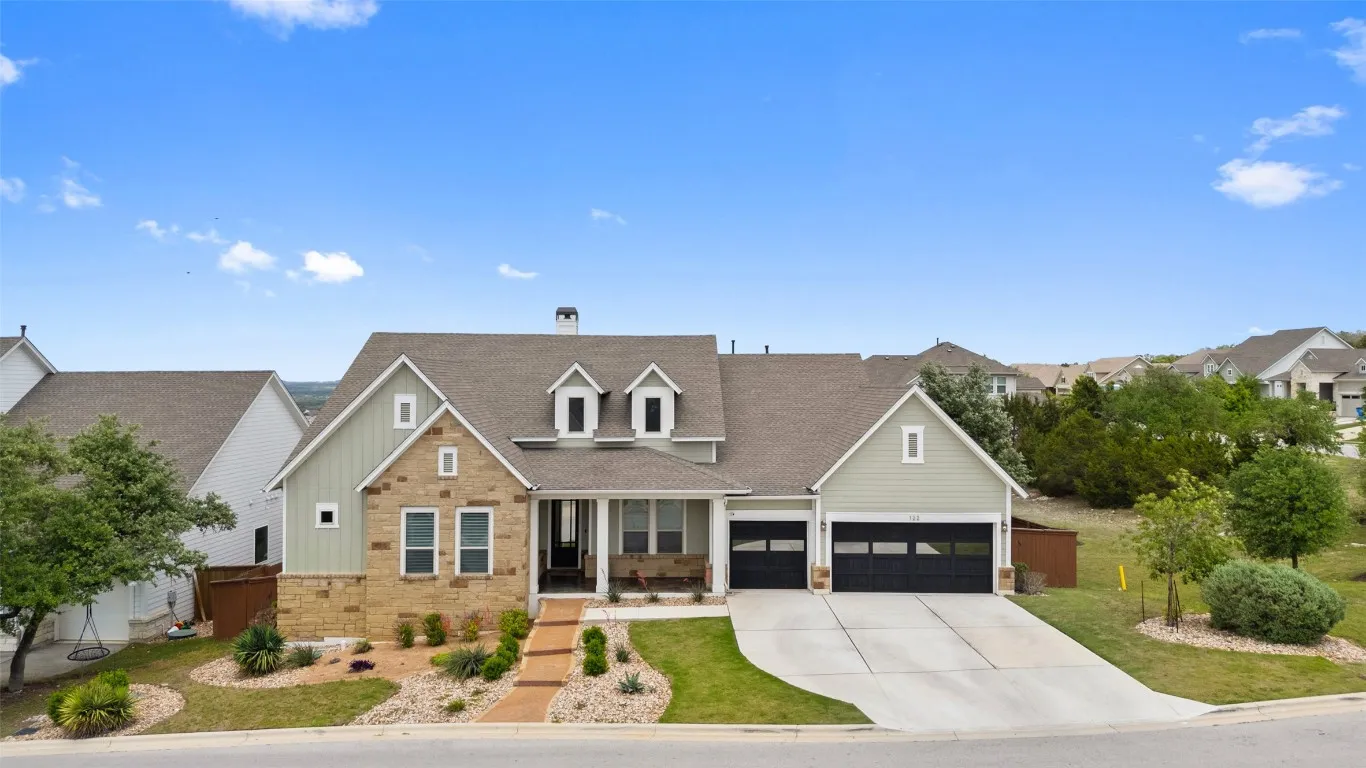 a view of a white house with a yard and table and chairs under an umbrella