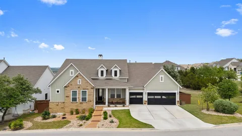 a view of a white house with a yard and table and chairs under an umbrella