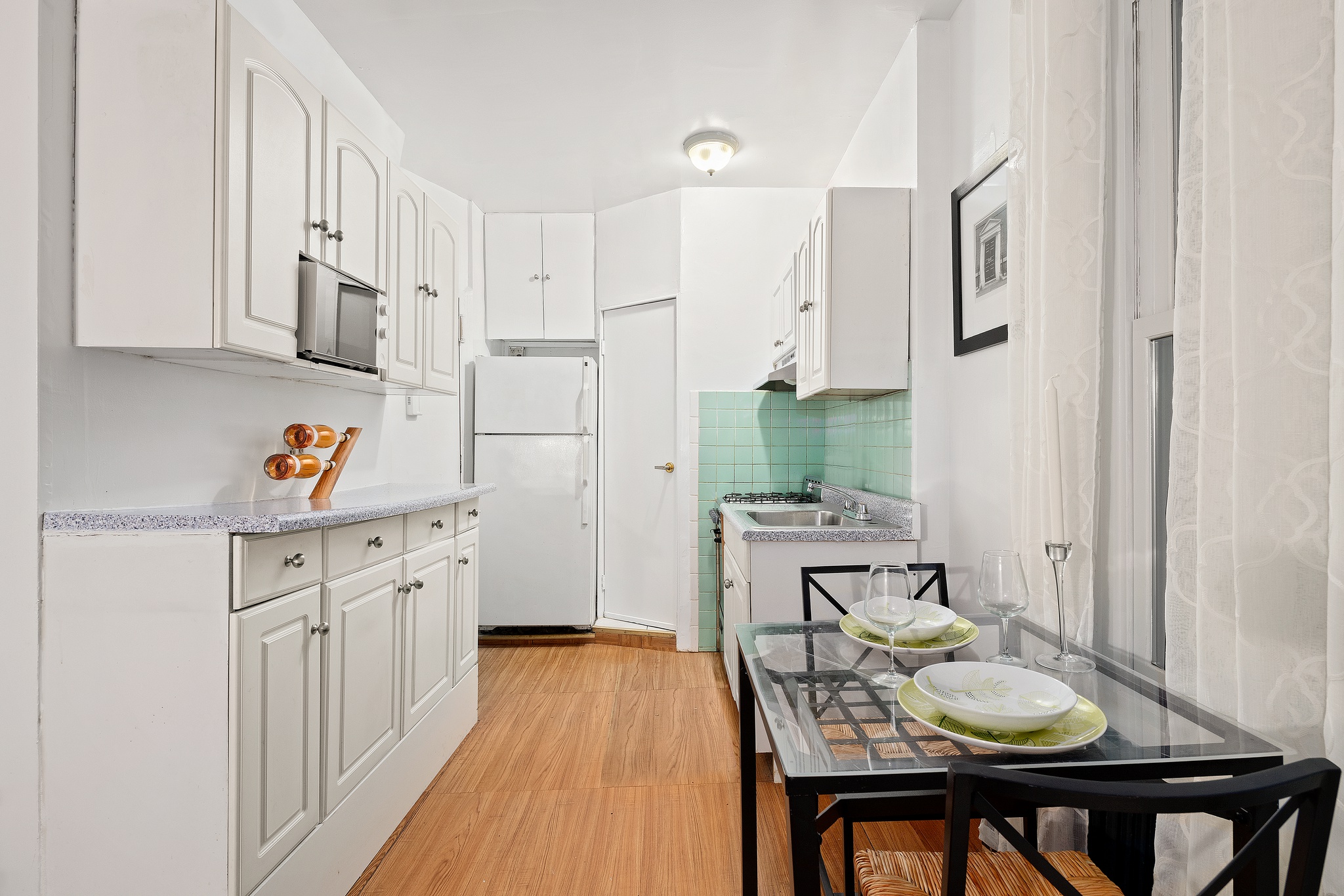 715 9th Avenue, Unit 2FN Manhattan, NY 10019 - Photo 3 of 11 a kitchen with stainless steel appliances granite countertop a white cabinets a sink dishwasher and wooden floor