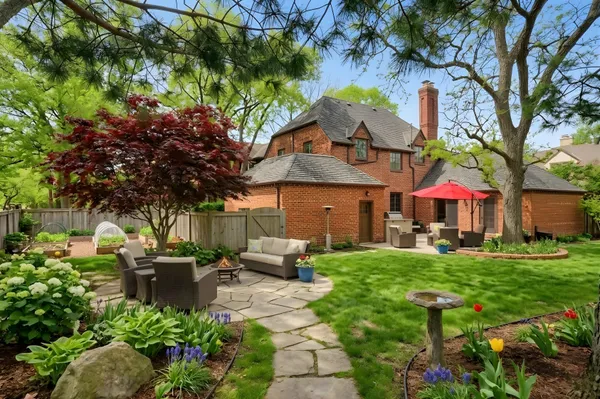 a view of a patio with table and chairs potted plants and large tree