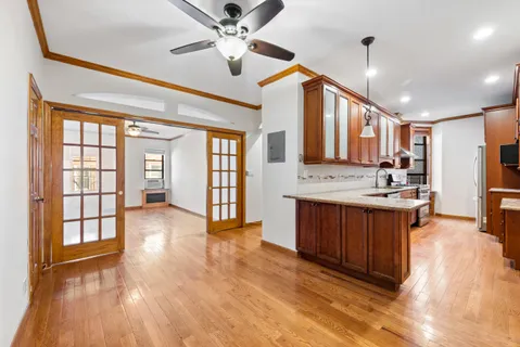 a large kitchen with stainless steel appliances granite countertop a stove top oven a sink a dining table and chairs with wooden floor