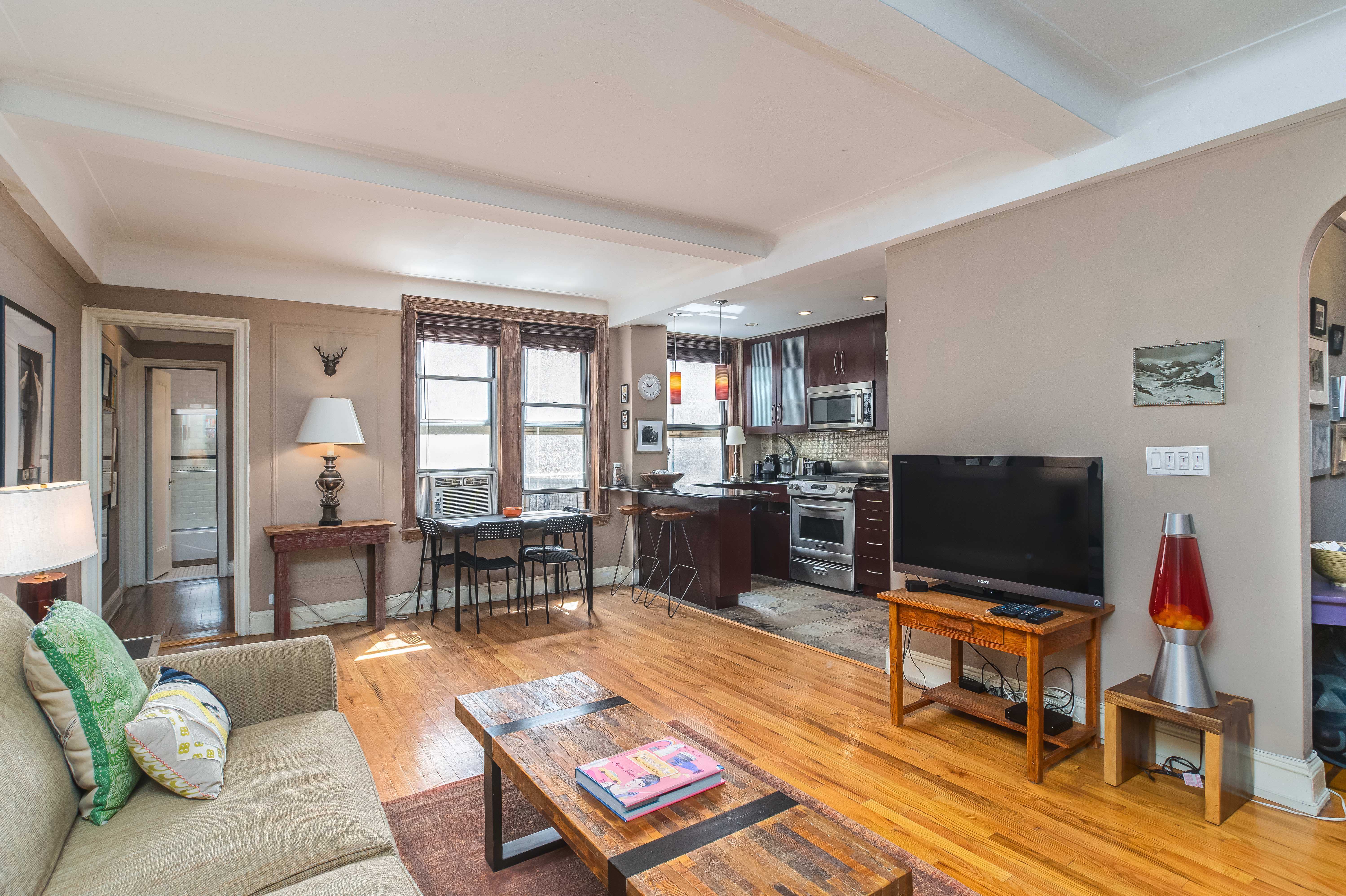 a living room with furniture a flat screen tv and a floor to ceiling window