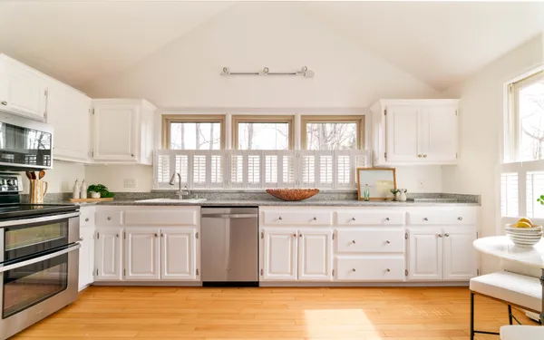 a large kitchen with granite countertop a stove top oven a sink a dining table and chairs