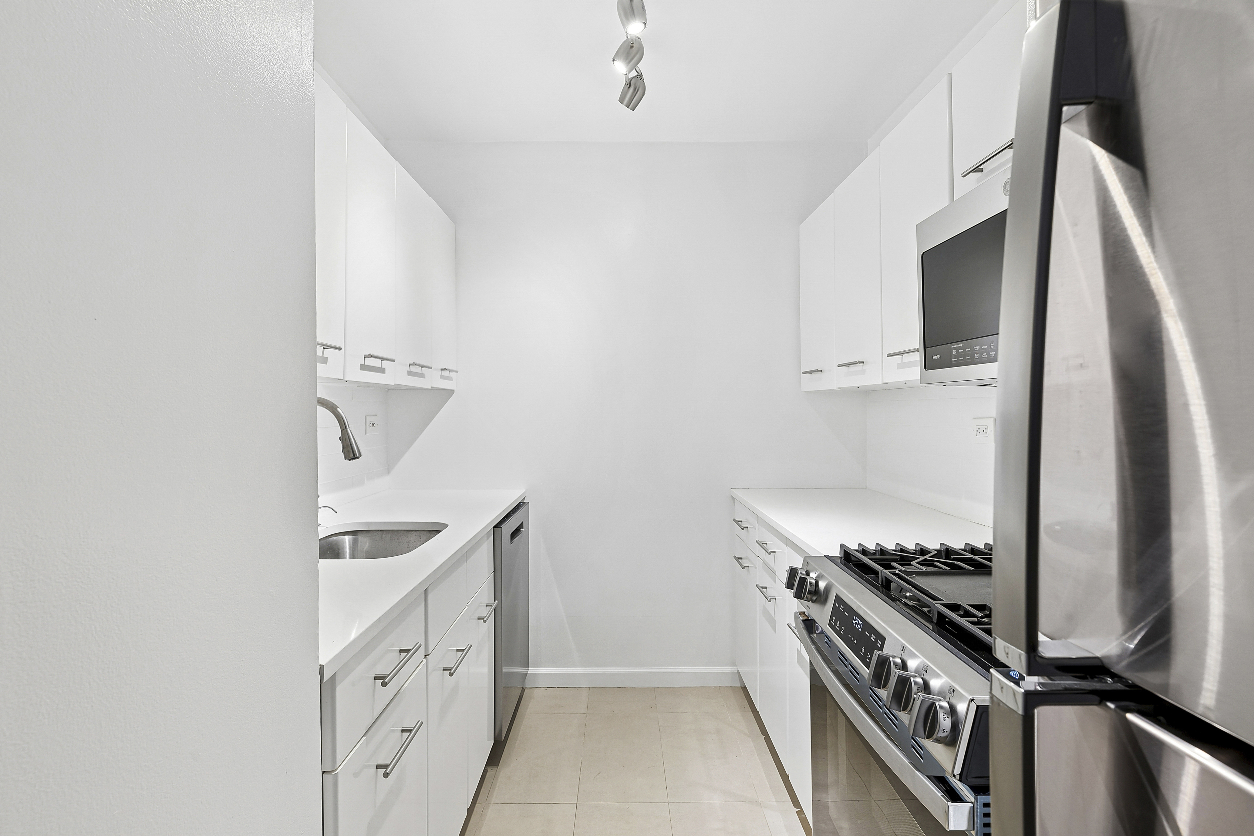 220 East 65th Street, Unit 8J Manhattan, NY 10065 - Photo 3 of 13 a kitchen with granite countertop a stove and a refrigerator