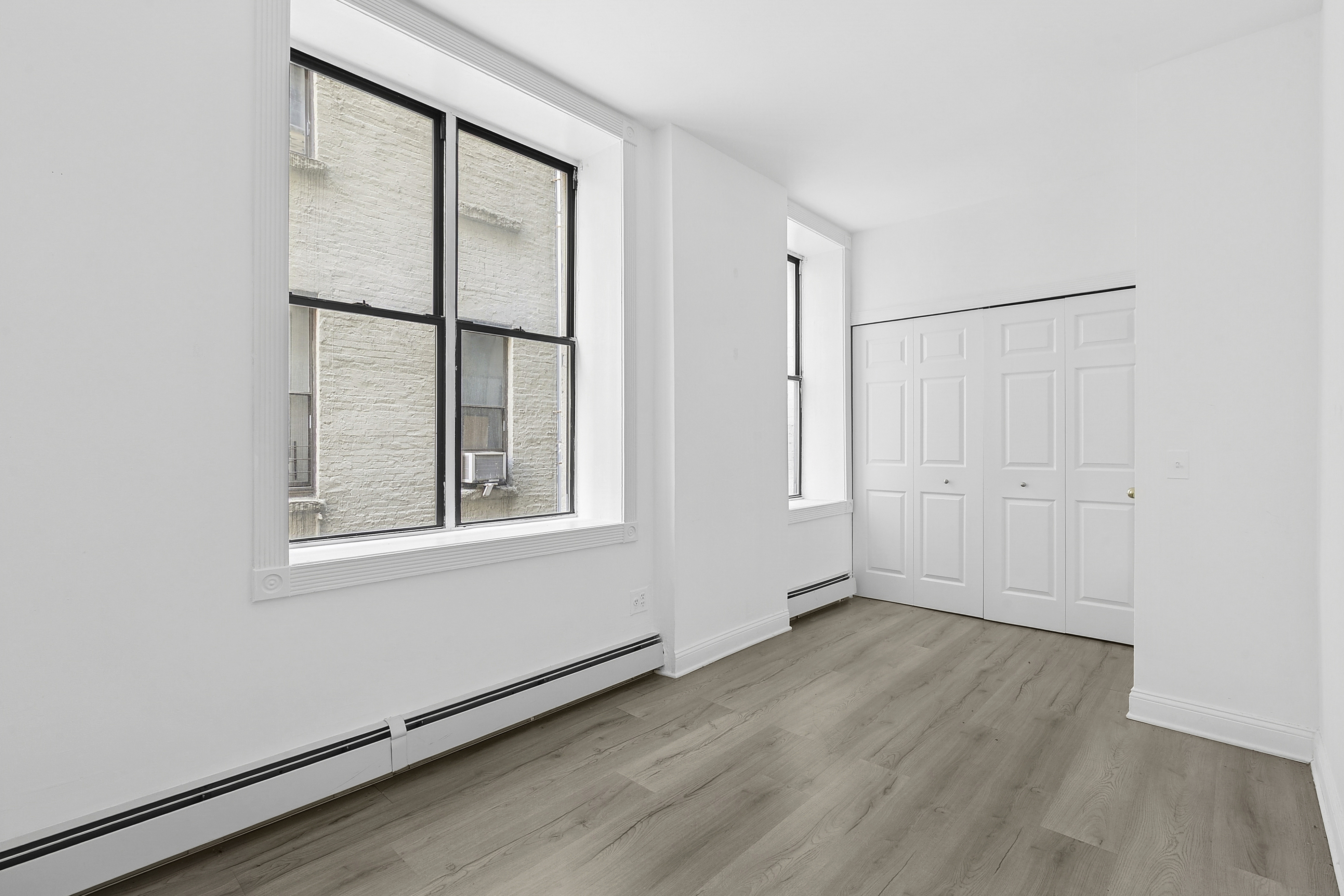 178 East 2nd Street, Unit 1B Manhattan, NY 10009 - Photo 8 of 11 an empty room with wooden floor and windows