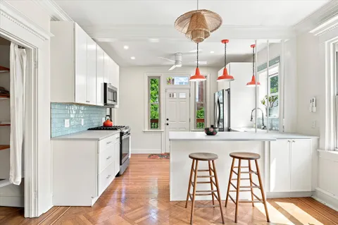 a kitchen view with stainless steel appliances kitchen island granite countertop a table chairs and a refrigerator
