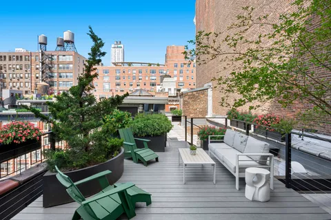 a roof deck with couches and potted plants with wooden floor and city view