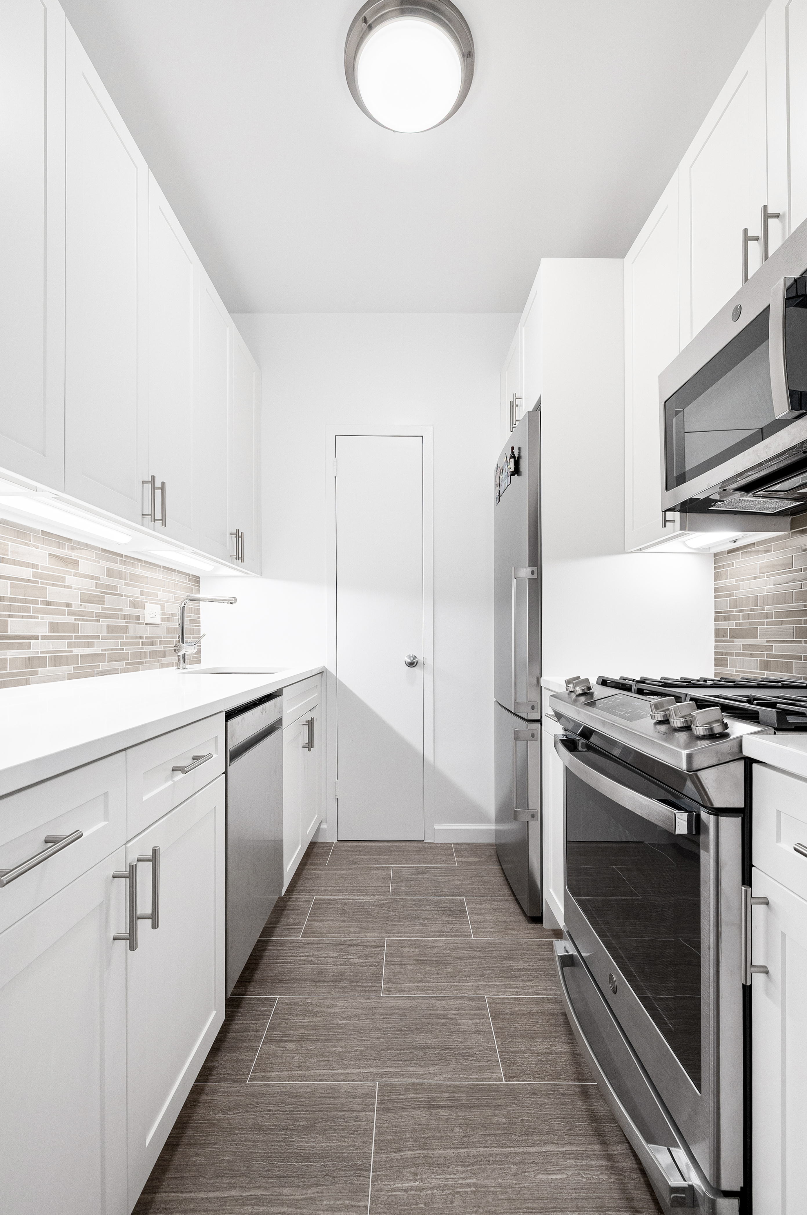 60 East 8th Street, Unit 15P Manhattan, NY 10003 - Photo 5 of 17 a large white kitchen with a stove top oven sink and refrigerator