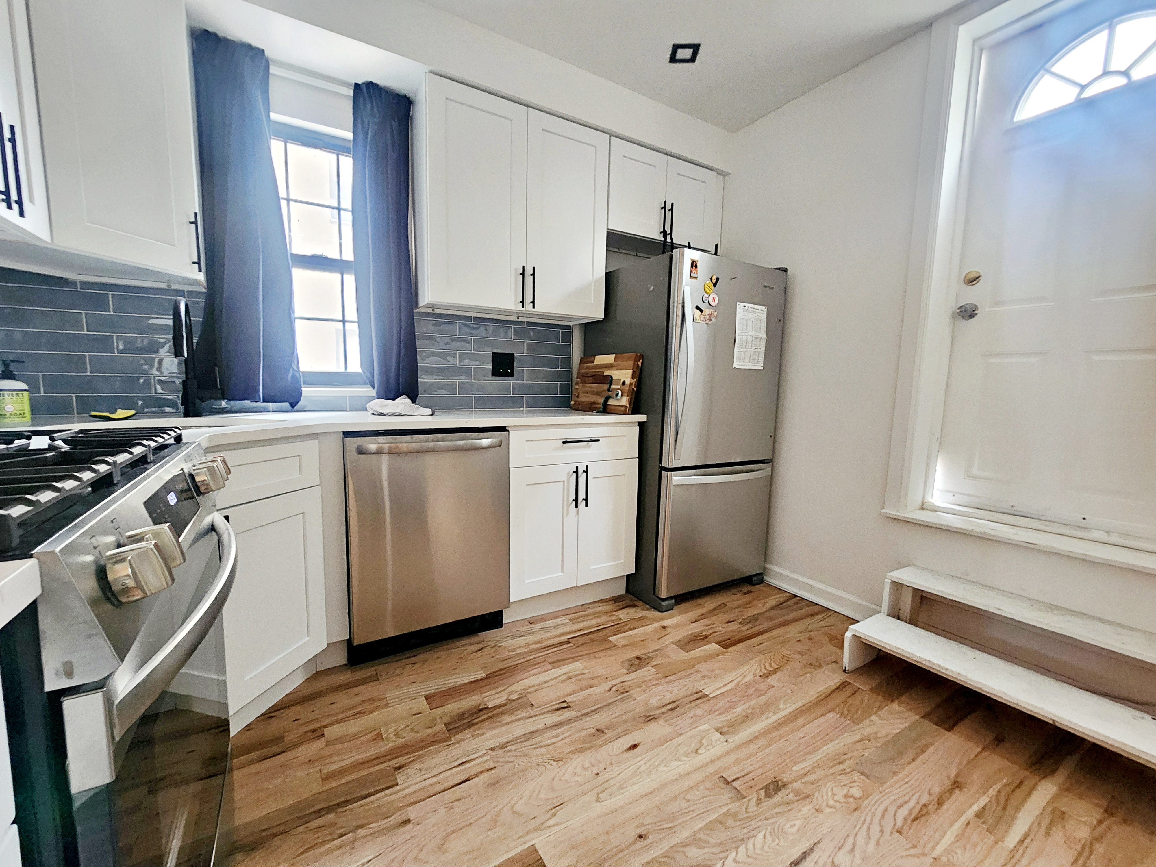 a kitchen with a sink wooden floor and stainless steel appliances
