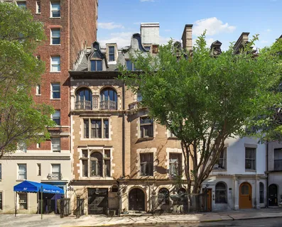a front view of a building with lot of trees