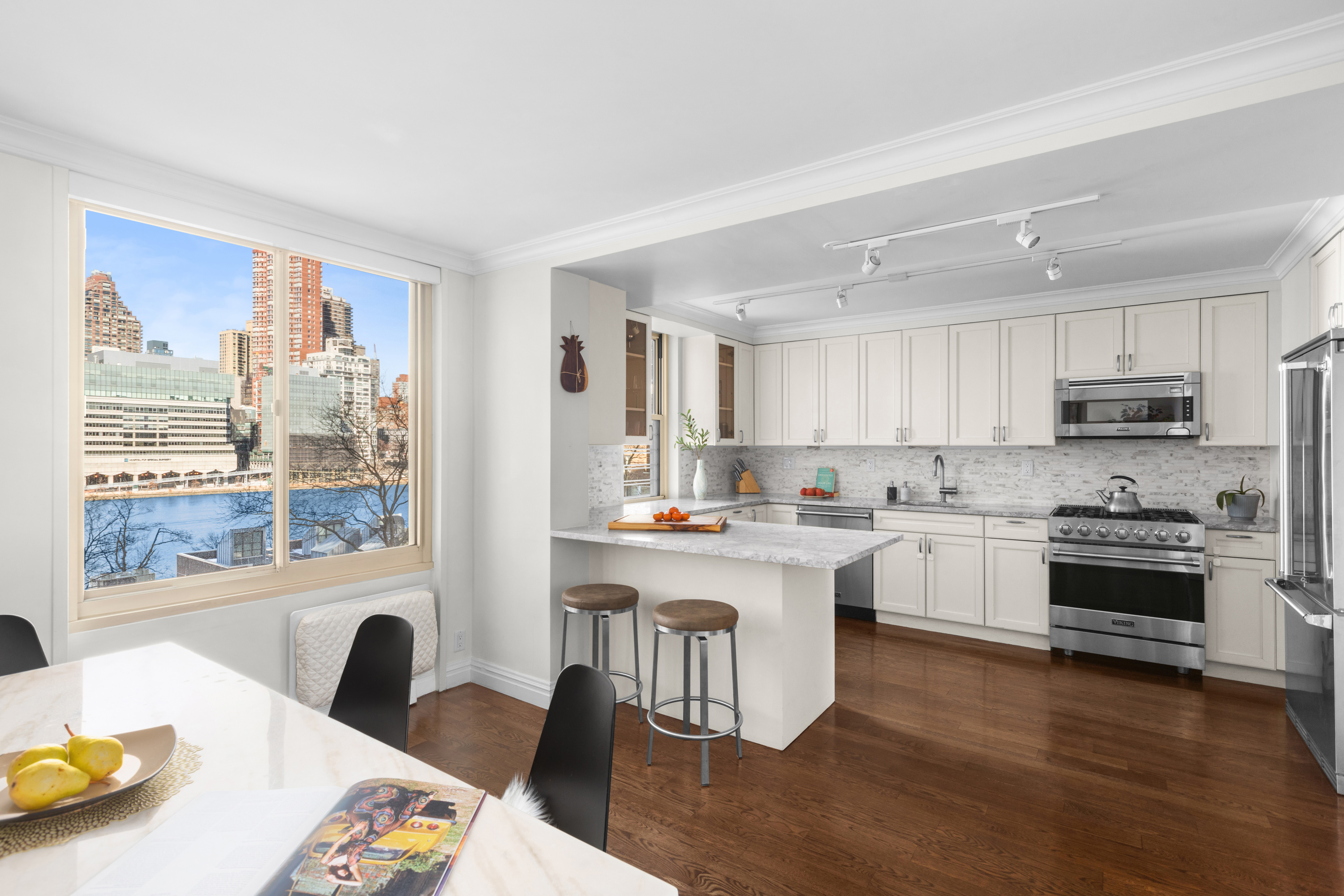 575 Main Street, Unit 509 Manhattan, NY 10044 - Photo 1 of 25 a kitchen with stainless steel appliances granite countertop a stove top oven a sink a dining table and chairs with wooden floor