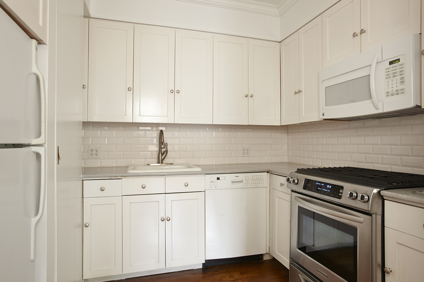 58 West 83rd Street, Unit 4A Manhattan, NY 10024 - Photo 4 of 9 a kitchen with white cabinets and white appliances