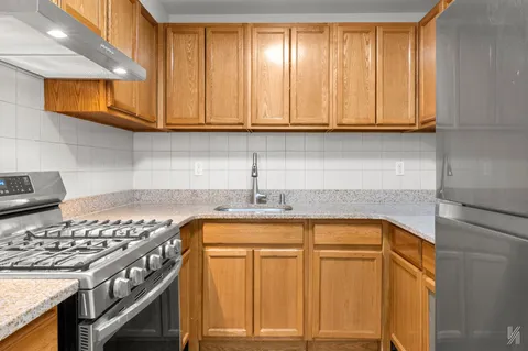 a kitchen with stainless steel appliances granite countertop a sink a stove cabinets and a wooden floor