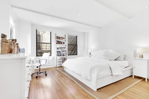 a bedroom with a bed a table and a large mirror