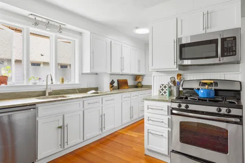 a kitchen with granite countertop white cabinets stainless steel appliances and a sink