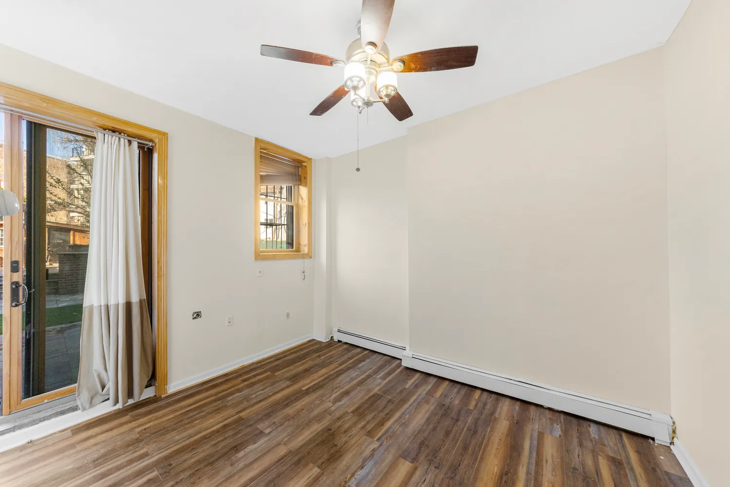 a view of empty room with wooden floor and fan
