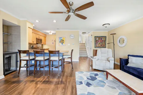 a living room with furniture kitchen view and a wooden floor